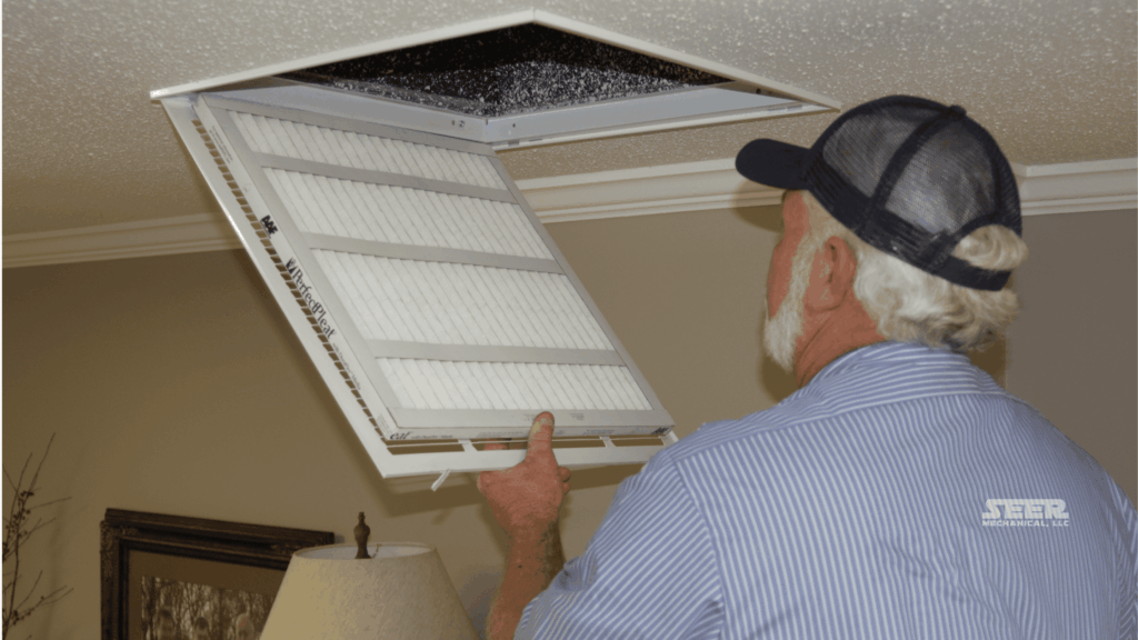 Technician replacing a residential ceiling return air filter during routine HVAC maintenance.