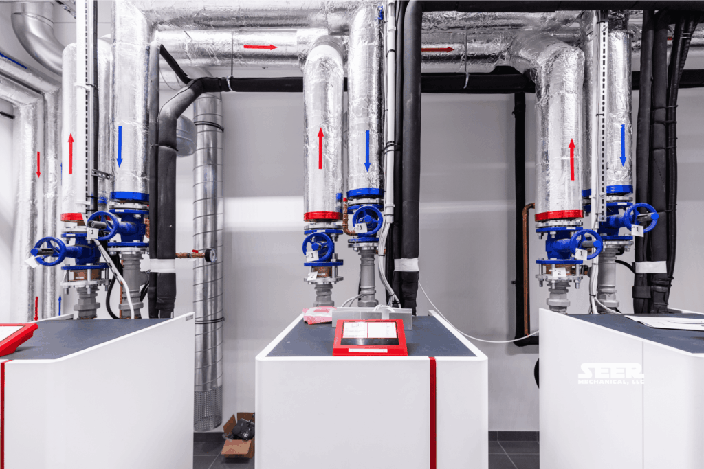 Commercial heat pump system with insulated pipes and control panels similar to those installed by Seer Mechanical.