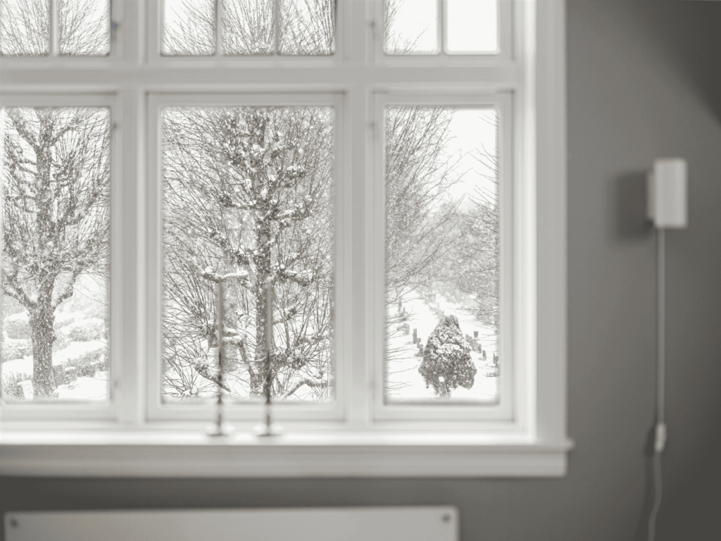 Cold winter landscape seen through a home window, representing heat escaping through inefficient windows